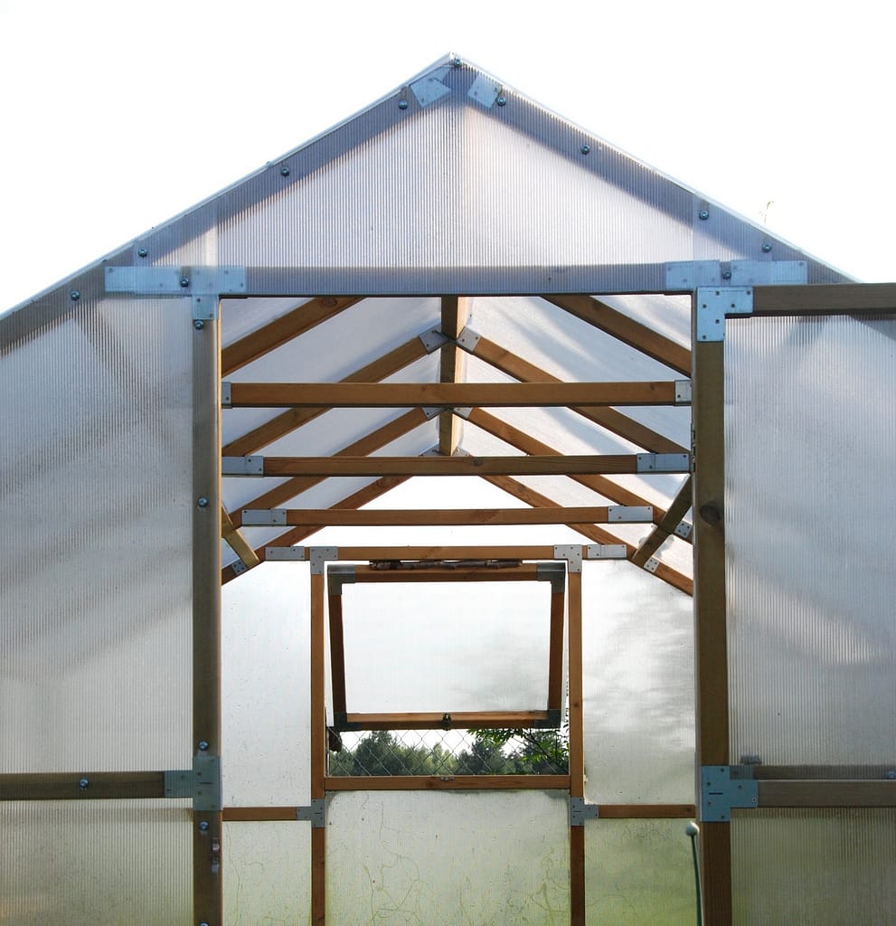 SZKLARNIE DREWNIANE Drewniana szklarnia typu domek z widoczną konstrukcją dachu i oknem wentylacyjnym z poliwęglanu